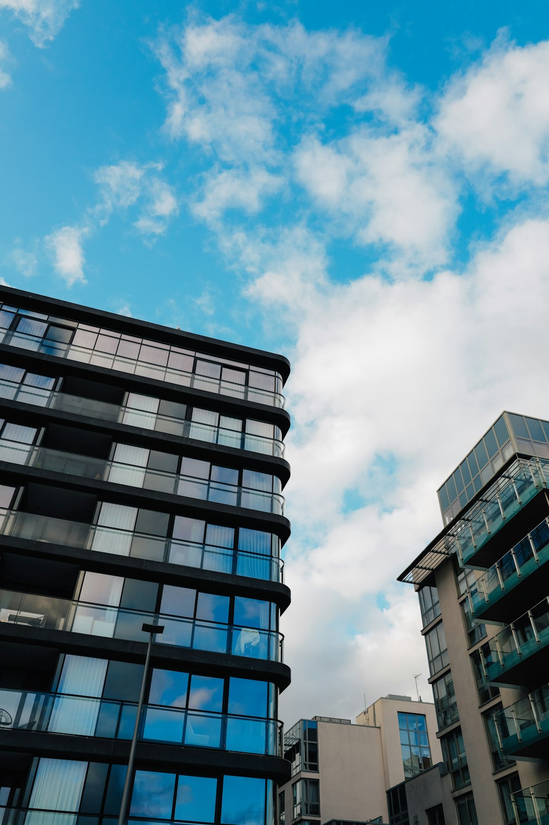 About modern-glass-buildings-against-a-blue-cloudy-sky-sqh5lj39t3i